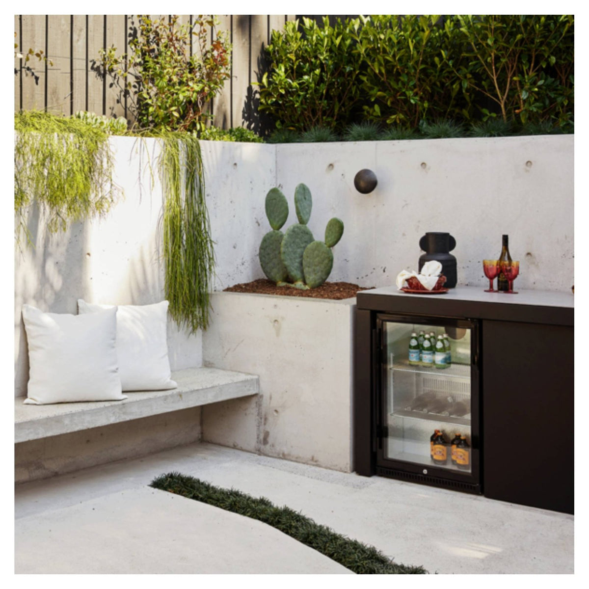 Artusi outdoor beverage chiller installed in a concrete and planted patio setting