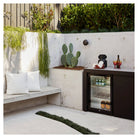 Artusi outdoor beverage chiller installed in a concrete and planted patio setting